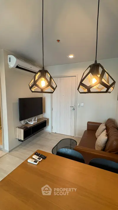 Modern living room with stylish lighting, leather sofa, and wall-mounted TV in a cozy apartment.