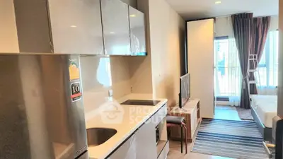 Modern studio apartment with sleek kitchen and cozy living area, featuring large windows for natural light.