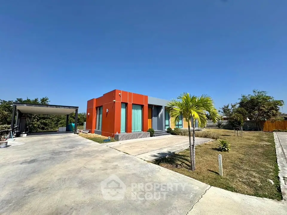Modern single-story home with vibrant orange facade and spacious driveway