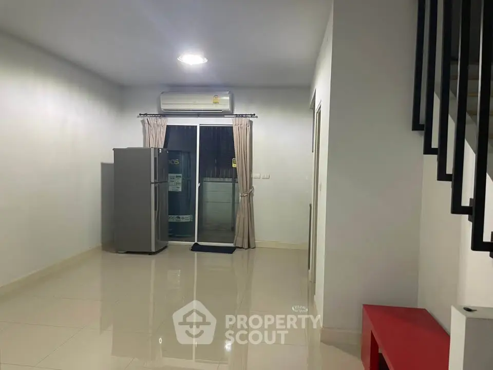 Spacious modern living area with sleek tiled flooring and large window for natural light.