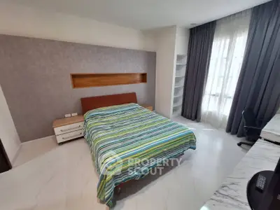 Spacious bedroom with modern decor and large window for natural light.