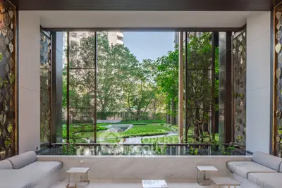 Luxurious building lobby with stunning garden view and elegant seating area.