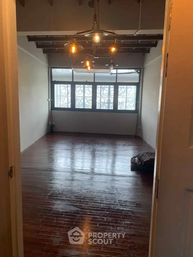 Spacious room with wooden floors and modern lighting, ideal for versatile living space.