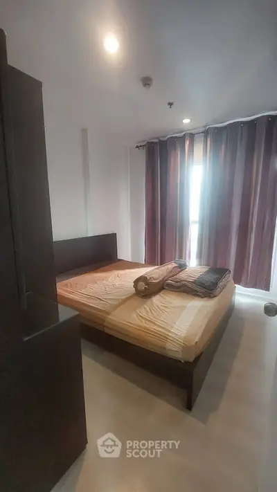 Cozy bedroom with large window and modern furnishings in a stylish apartment.