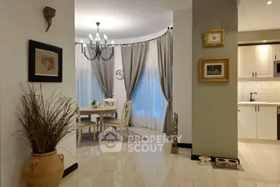 Elegant dining area with chandelier and modern kitchen in open layout apartment.