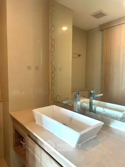 Modern bathroom with sleek sink and large mirror in a stylish apartment.