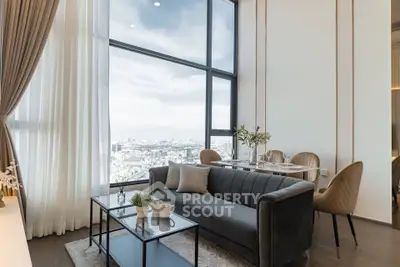 Luxurious living room with floor-to-ceiling windows offering stunning city views, elegant decor, and cozy seating.