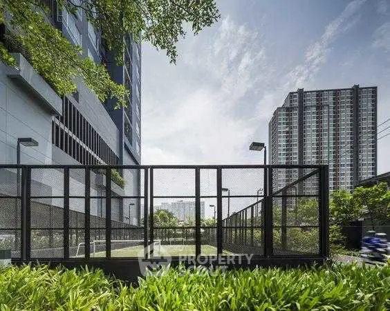 Modern urban apartment building with outdoor sports court and lush greenery.