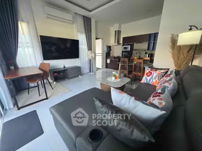 Modern living room with open kitchen, stylish decor, and large TV in a cozy apartment.