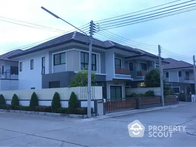 Modern two-story house with a fenced yard in a suburban neighborhood.