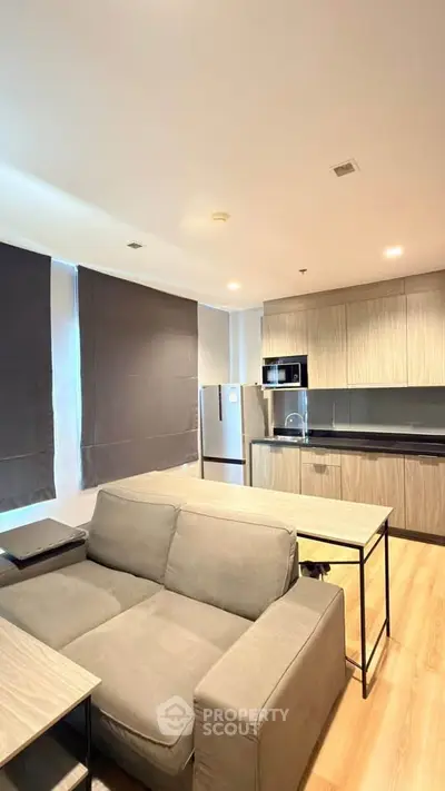 Modern open-layout living room with sleek kitchen and cozy seating area, perfect for urban living.