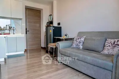 Modern living room with cozy sofa and compact kitchen in open layout apartment.