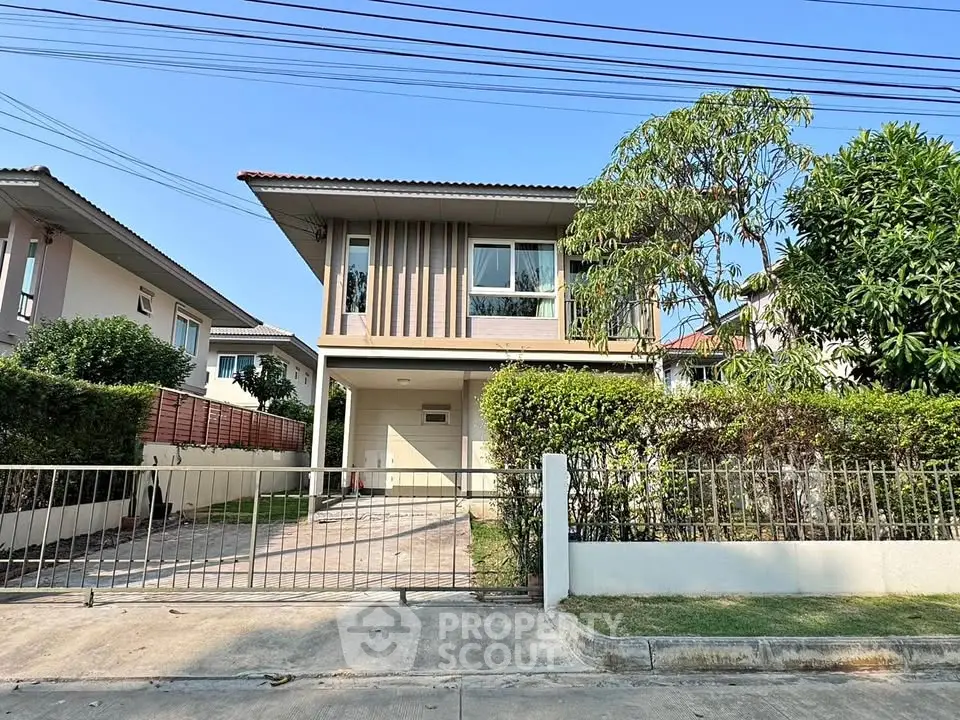Charming two-story house with lush garden and gated driveway in serene neighborhood.