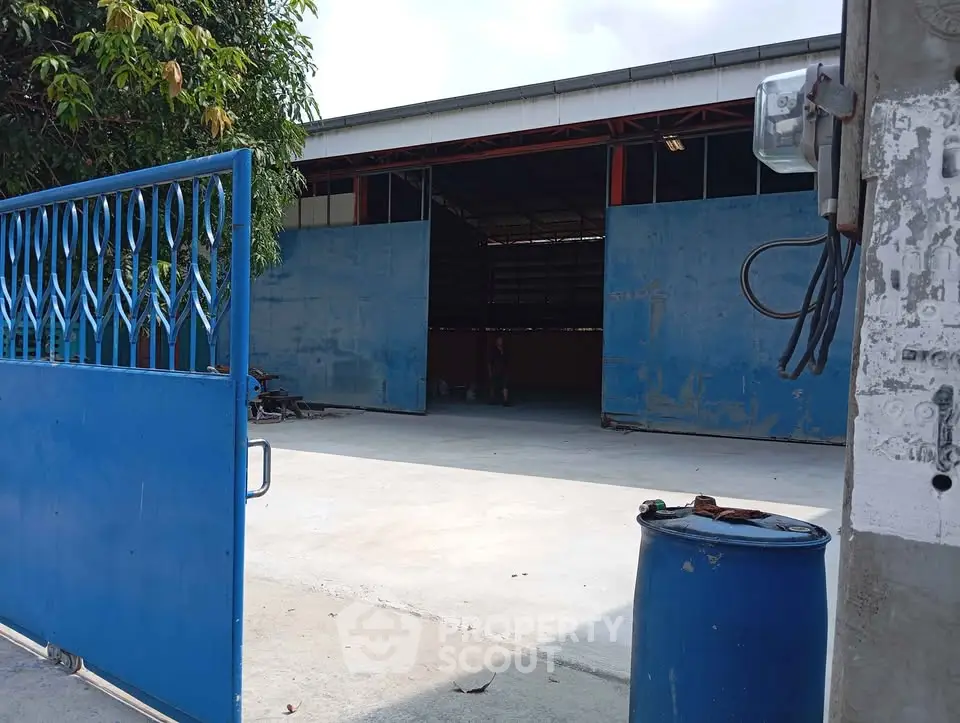 Spacious industrial warehouse with open blue gates and ample outdoor space.