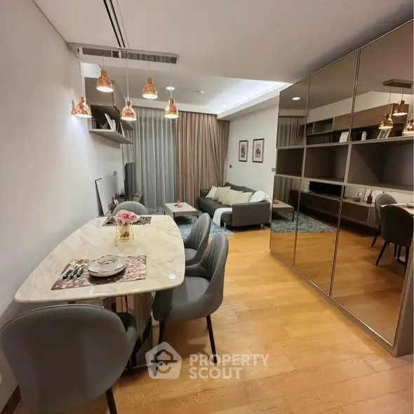 Modern living room with dining area, stylish lighting, and mirrored storage.