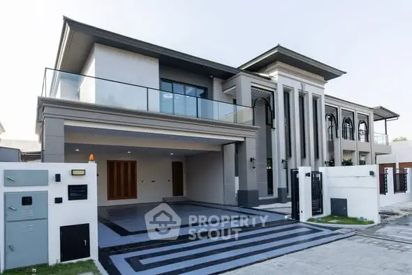 Luxurious modern mansion with grand entrance and spacious driveway, featuring sleek architectural design and large windows.