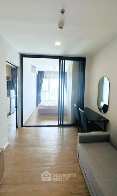 Modern apartment interior with open layout, featuring a cozy living area and a bedroom with large windows.