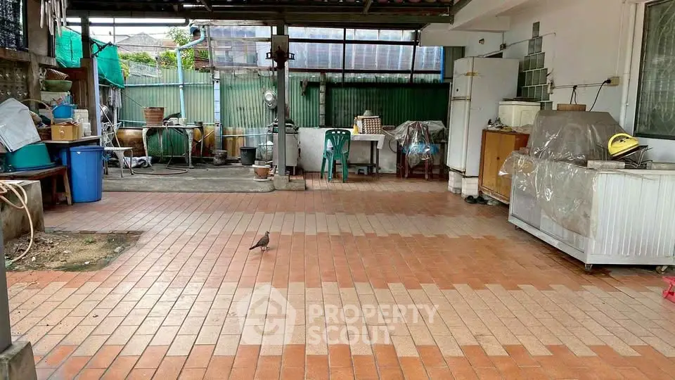 Spacious outdoor area with tiled flooring and covered patio, ideal for versatile use and storage.