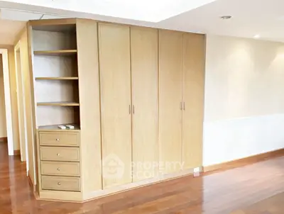 Spacious bedroom with built-in wooden wardrobe and elegant hardwood flooring.