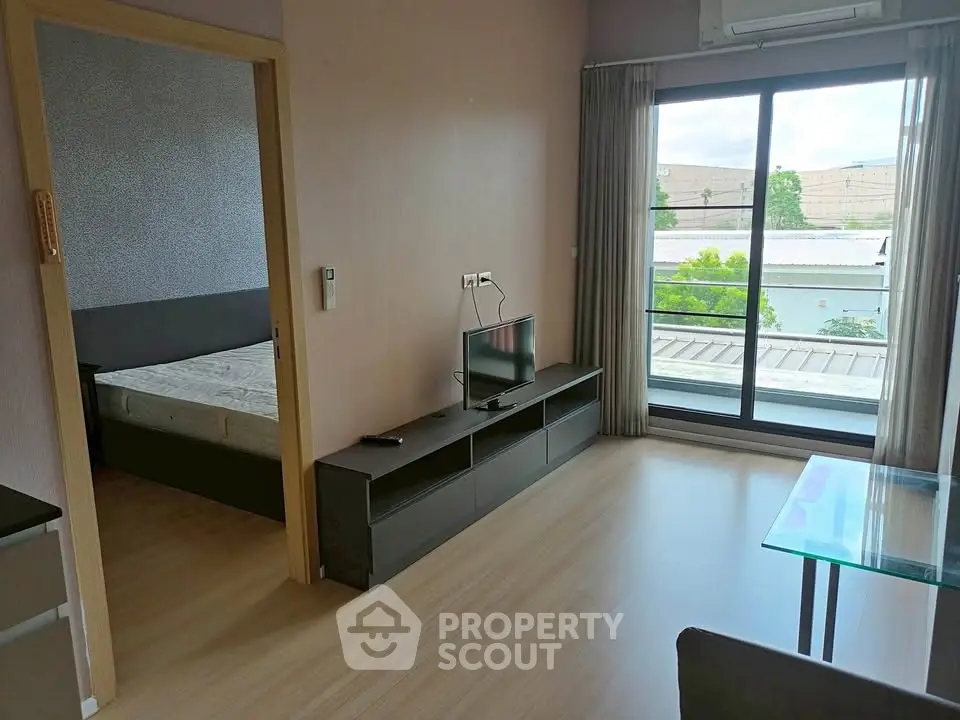 Modern apartment interior with bedroom and living area, featuring large window and sleek furniture.