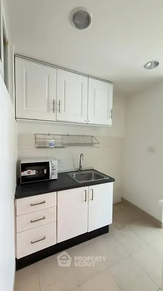 Compact kitchen with white cabinets and modern appliances in a cozy apartment.