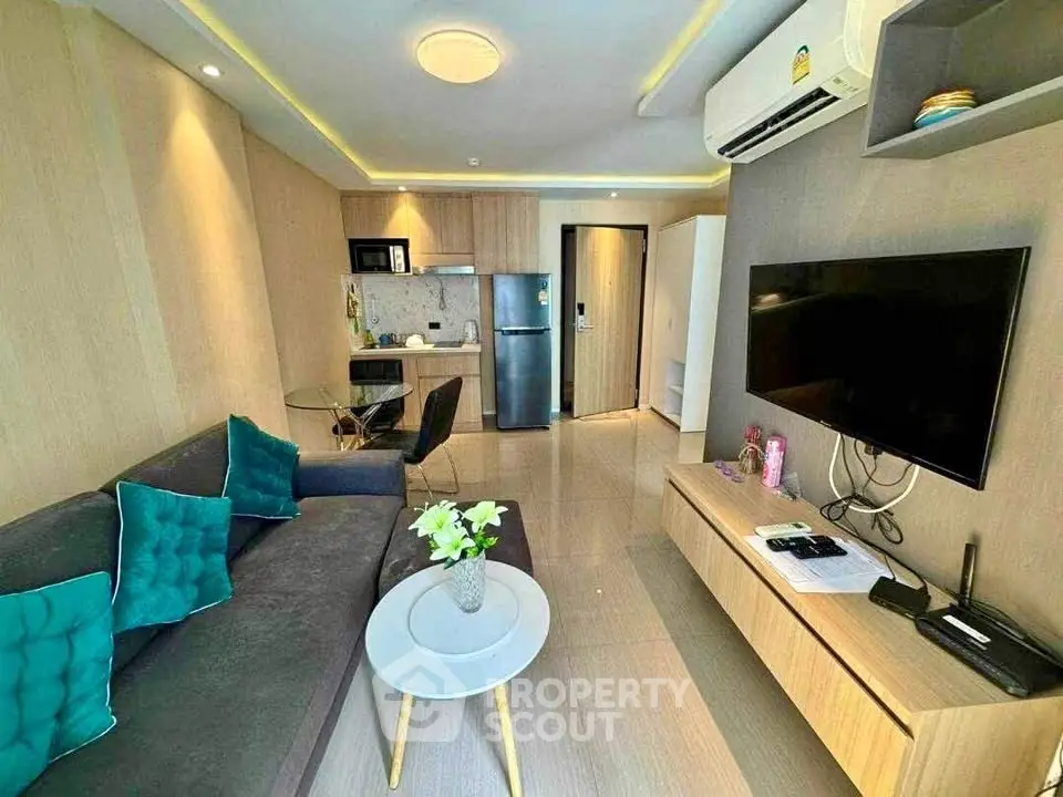 Modern living room with open kitchen, featuring sleek furniture and air conditioning.