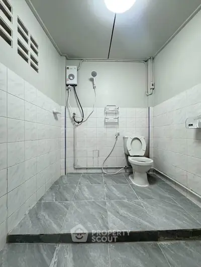 Spacious bathroom with modern fixtures and tiled flooring, featuring a shower and toilet.