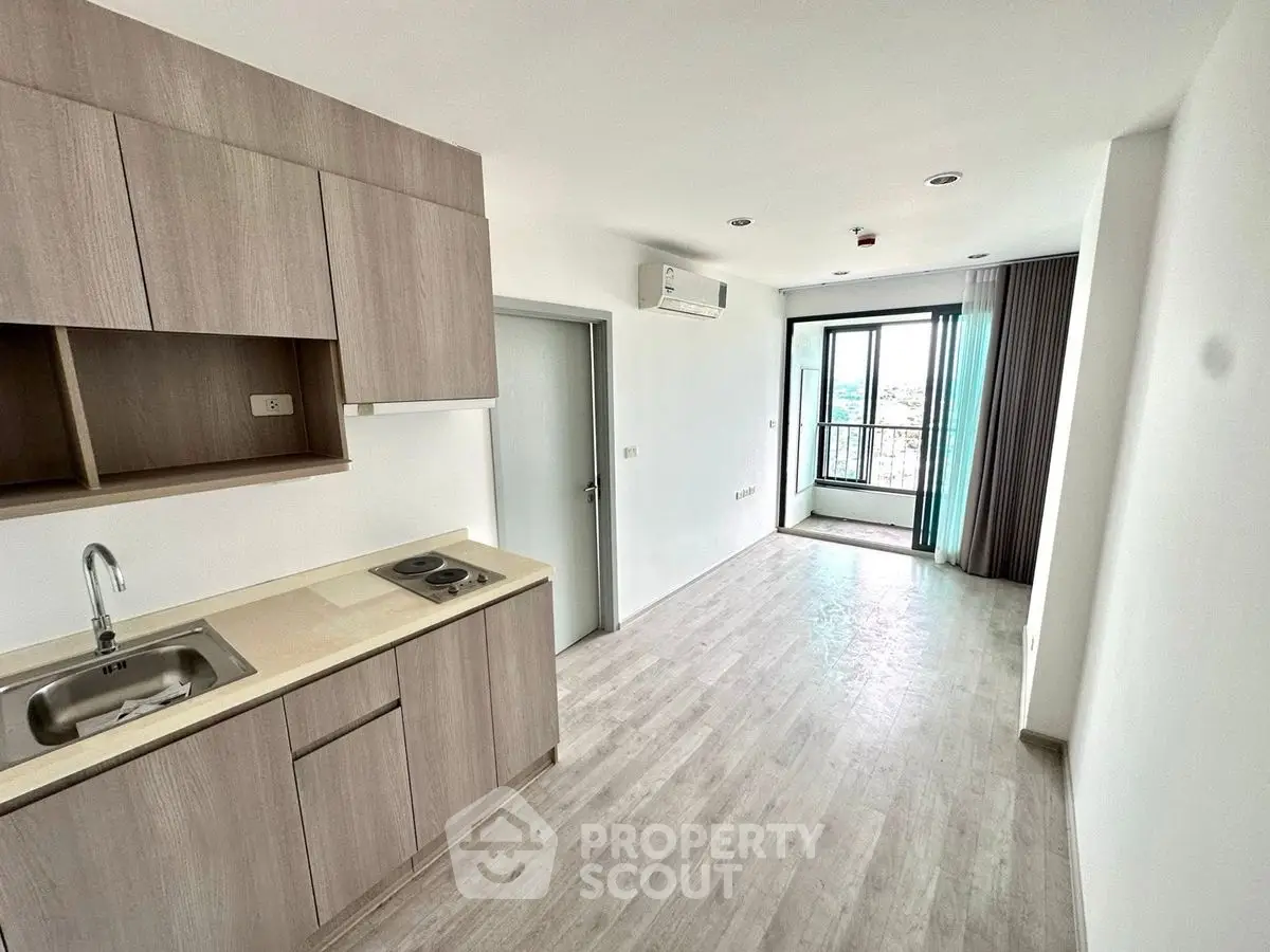 Modern open-plan kitchen and living area with large window and sleek wooden flooring.