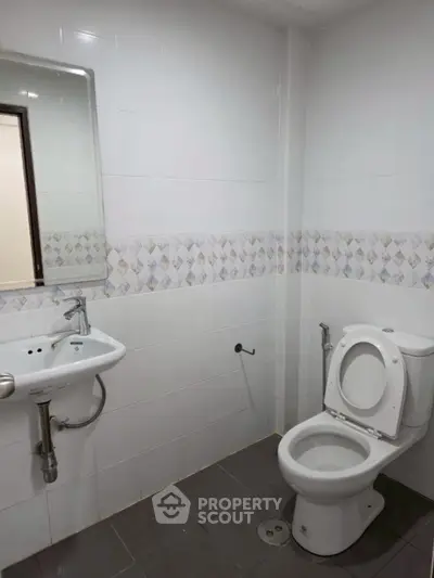 Modern bathroom with white tiles and sleek fixtures in a real estate property.