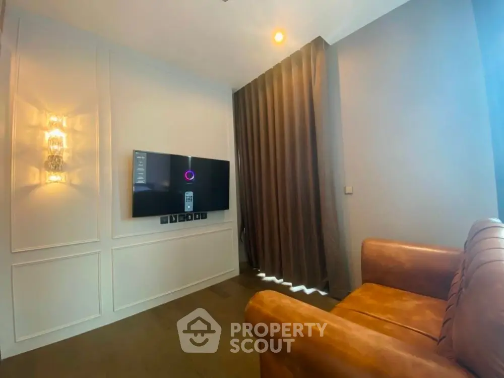 Modern living room with leather sofa and wall-mounted TV, featuring elegant lighting and floor-to-ceiling curtains.