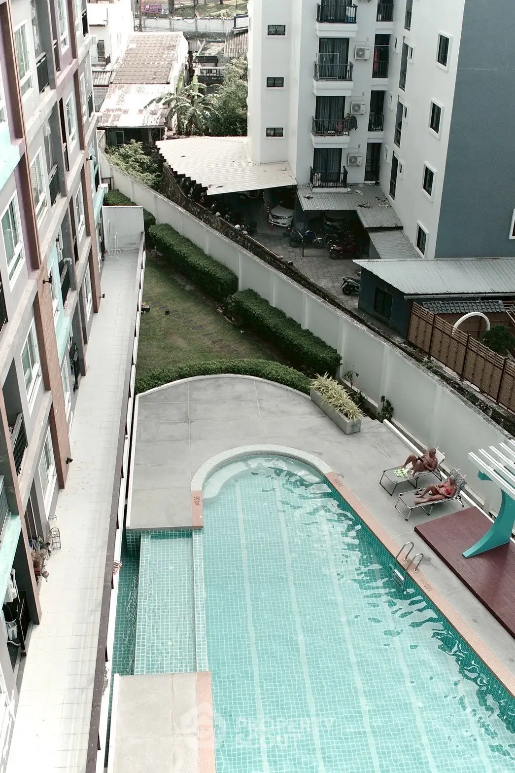 Stunning aerial view of modern apartment complex with inviting swimming pool and lush greenery.