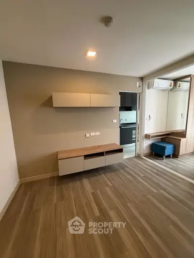 Modern living room with sleek wooden flooring and built-in storage units.