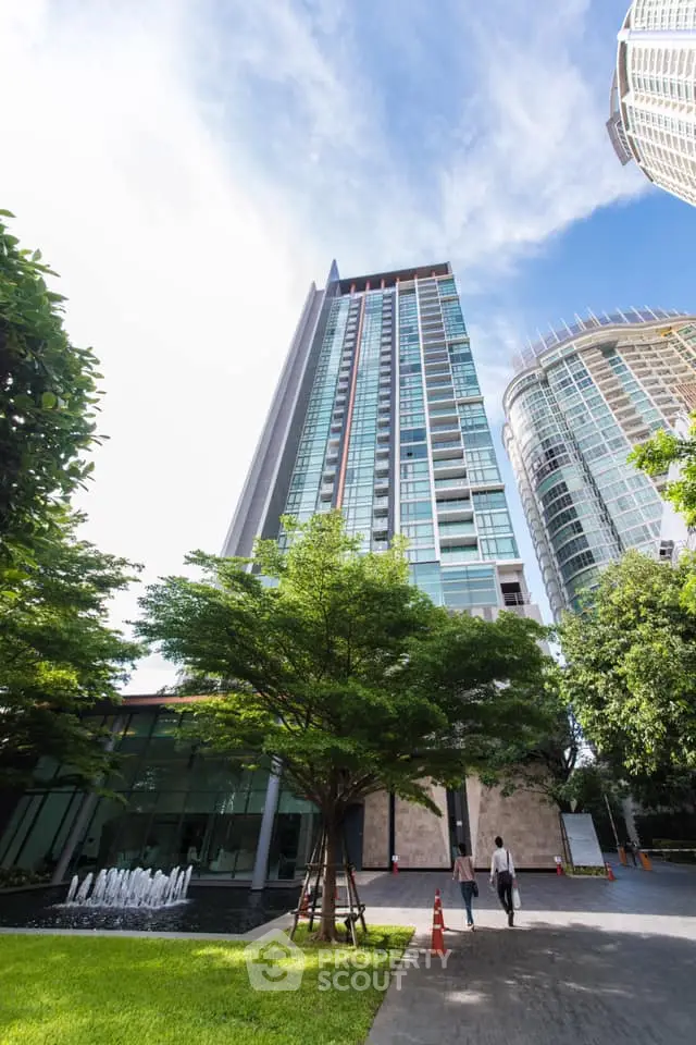 Stunning modern high-rise building with lush greenery and clear blue sky.