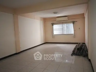 Spacious empty room with tiled flooring and window, ideal for customization.