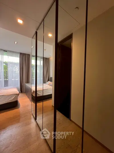 Spacious bedroom with mirrored closet and large windows for natural light.