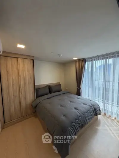 Cozy bedroom with large window and modern wooden wardrobe