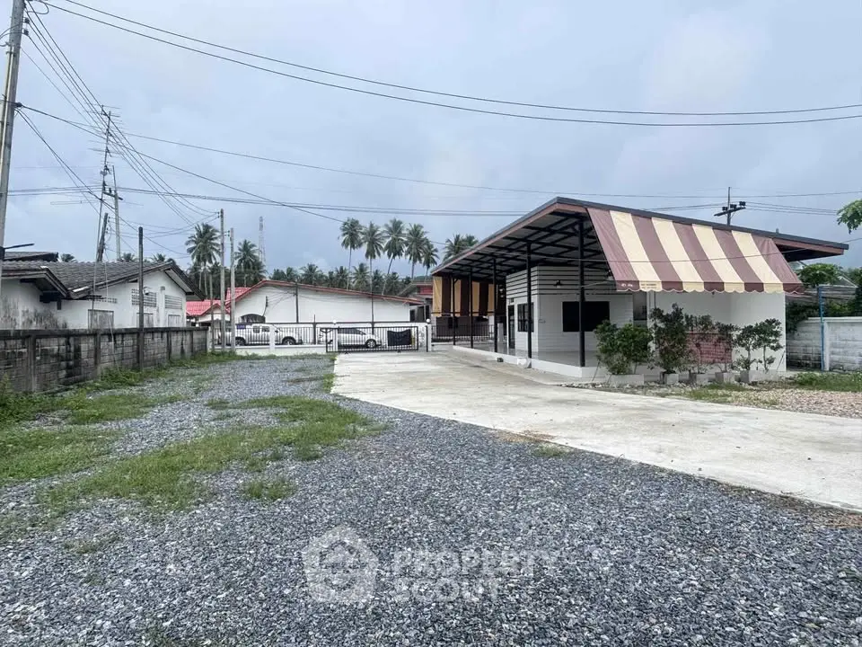 Charming single-story home with spacious driveway and tropical surroundings.