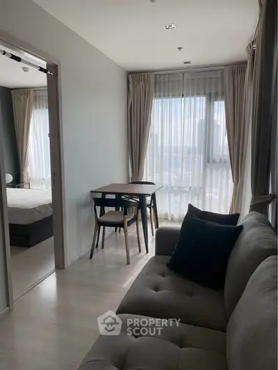Modern apartment living room with cozy sofa and dining area, featuring large windows with city view.