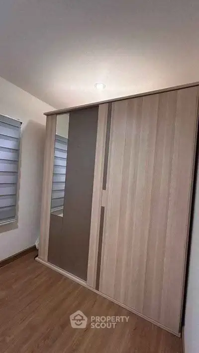 Modern bedroom with sleek wooden wardrobe and stylish window blinds.