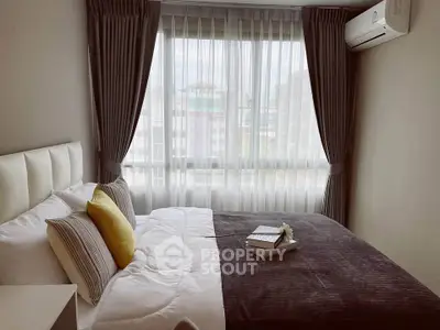 Cozy bedroom with modern decor and large window offering natural light.