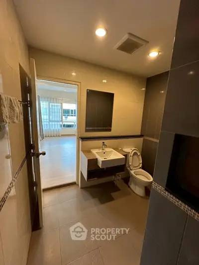 Modern bathroom with sleek fixtures and view into a bright living space.