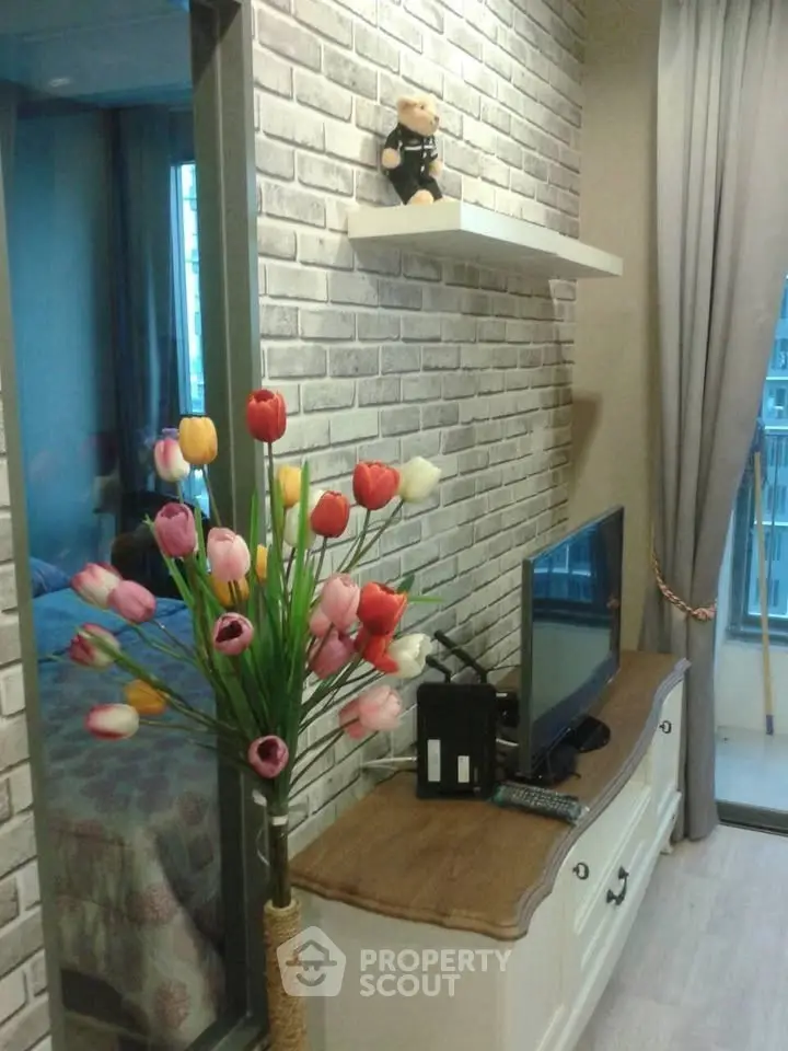 Charming living room with brick accent wall, modern TV setup, and vibrant tulip decor.