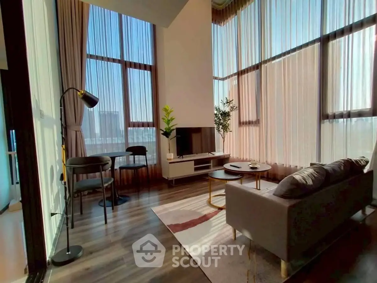 Spacious modern living room with high ceilings and large windows, featuring elegant decor and abundant natural light.