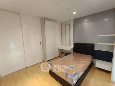 Modern bedroom with sleek design, featuring a bed, wardrobe, and stylish shelving.