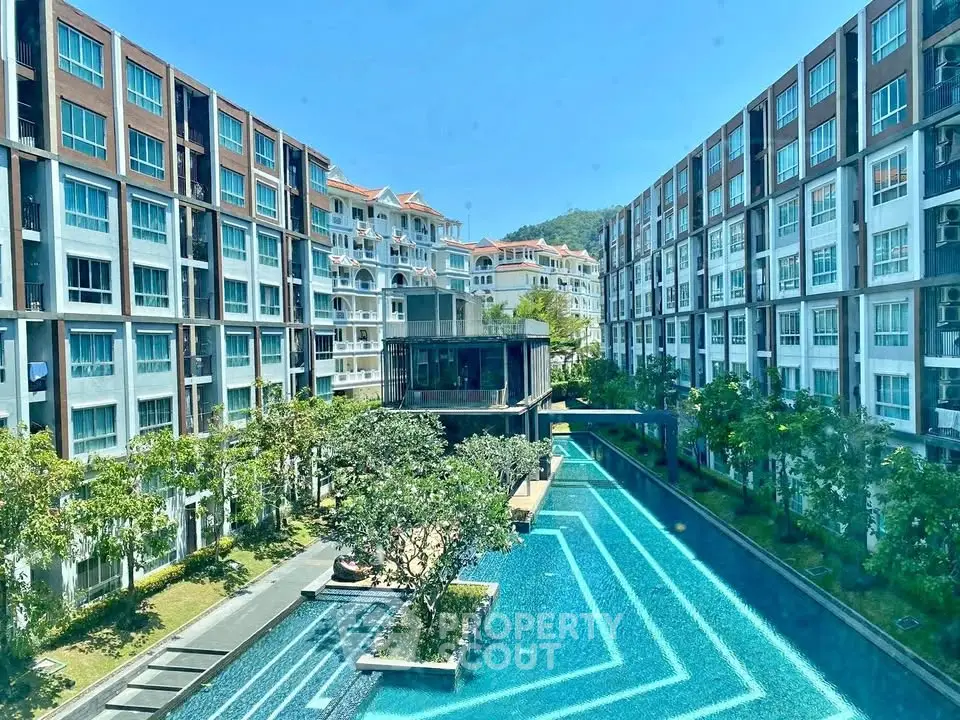 Luxurious condominium complex with stunning pool and lush greenery, offering a serene living environment.