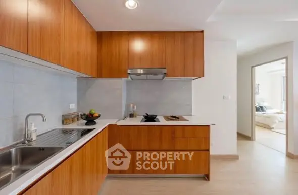 Modern kitchen with sleek wooden cabinets and integrated appliances in a stylish apartment.