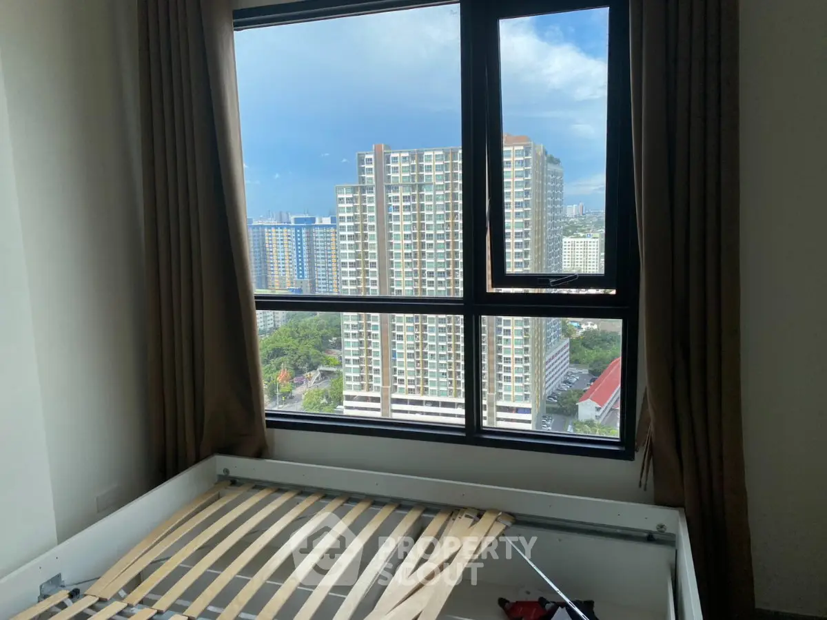 High-rise apartment bedroom with stunning city view through large window.