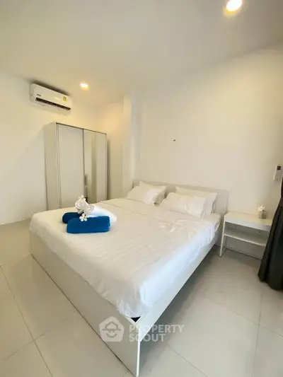 Modern bedroom with white decor, air conditioning, and stylish furnishings for a cozy living experience.