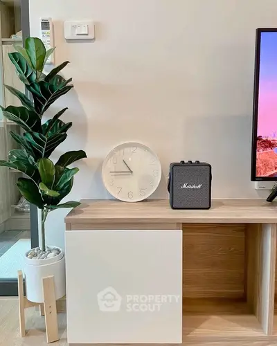 Modern living room with stylish decor, featuring a sleek cabinet, indoor plant, and wall-mounted clock.
