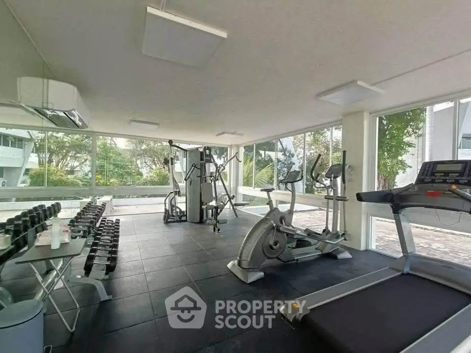 Modern gym with large windows and exercise equipment in a residential building.